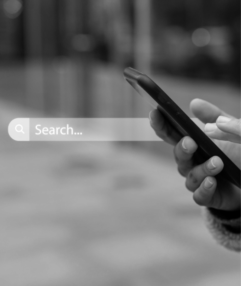 Person using a smartphone with a visible search bar on screen, representing online search and how users look for information and brands on the internet.