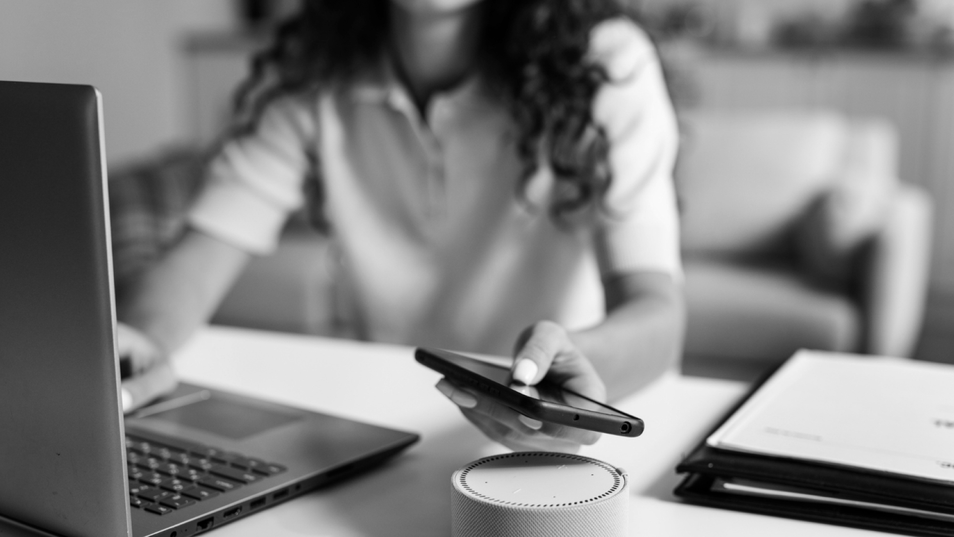 Utilizadora a interagir com um assistente de voz num smartphone junto a um portátil, representando a pesquisa por voz e o impacto da inteligência artificial na forma como procuramos informação online.