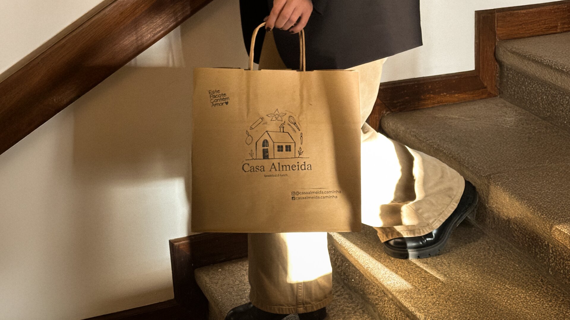 Pessoa a segurar um saco de papel da Casa Almeida.
